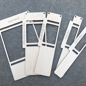 May include: A set of five light-colored wooden macrame project boards with cut-out rectangular centers and pre-drilled holes. The boards are engraved with the text project board, alternating square knot, double half hitch, half knot, and square knot.