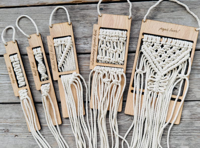 May include: Five rectangular wooden boards with hanging loops, each featuring different cream-colored macrame knot patterns. The boards are labeled with text including square knot, half knot, double half hitch, alternating square knot, and project board.
