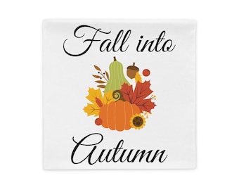 Op de afbeelding: Wit kussen met een herfstontwerp. Het ontwerp bevat een oranje pompoen, een groene kalebas, herfstbladeren en de woorden "Fall into Autumn" in zwart script.