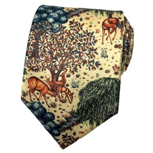May include: A necktie featuring a cream-colored background with a detailed forest scene print. The pattern includes brown deer grazing near a large tree, dark green bushes, and a weeping willow tree, all rendered in a classic, intricate illustration style.