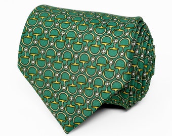 May include: A rolled necktie featuring a vibrant green background with a repeating pattern of gold-colored horse bit motifs and small white circular accents. The fabric has a visible woven texture, and the tie is folded to display the pointed end.