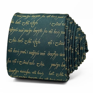 Può includere: Cravatta verde scuro con scritta elfica dorata. La cravatta è piegata, mostrando un motivo ripetuto della scritta. Il tessuto è liscio, adatto alle occasioni formali. Ispirato alla letteratura fantasy.