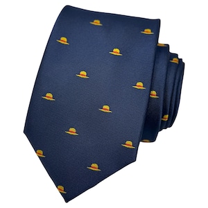 Può includere: Una cravatta blu navy con un motivo ripetuto di cappelli da sole gialli e arancioni. La cravatta è piegata, mostrando la trama del tessuto e il design dei cappelli uniformemente distanziati. Un accessorio classico con un tocco di fantasia.
