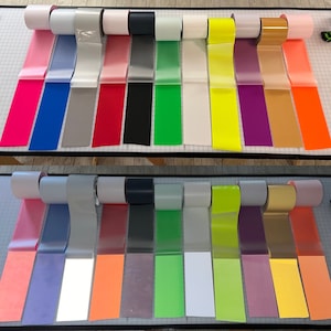 以下が含まれることがあります： 異なる色の反射テープのロールが2列あります。 上段には、ピンク、ブルー、グレー、レッド、ブラック、グリーン、ホワイト、イエロー、パープル、ゴールド、オレンジがあります。 下段には、ピンク、ライトブルー、グレー、レッド、ブラック、グリーン、ホワイト、イエロー、パープル、ゴールド、オレンジがあります。