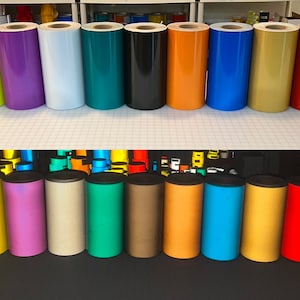 May include: Rolls of reflective vinyl in various colors, including yellow, purple, white, green, black, orange, blue, gold, red, and silver. The rolls are arranged in two rows on a table.