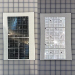 May include: Two sheets of stickers. One sheet has six rectangular stickers with a dark, textured pattern. The other sheet has six stickers with a shiny, silver pattern. Each sticker has a small, circular emblem.