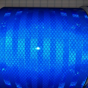 Puede incluir: Un rollo de cinta reflectante azul con un patr&oacute;n de diamante. La cinta se utiliza para la seguridad y la visibilidad.