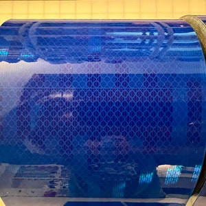 Puede incluir: Un rollo de cinta reflectante azul con un patr&oacute;n de diamante. La cinta est&aacute; enrollada y lista para ser utilizada.