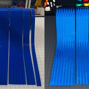 Puede incluir: Cuatro rollos de cinta reflectante azul, mostrados tanto a la luz del d&iacute;a como bajo una luz negra. La cinta tiene un patr&oacute;n rayado y est&aacute; dise&ntilde;ada para la seguridad y la visibilidad.