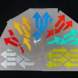 May include: A set of six reflective arrow stickers in various colors, including yellow, blue, red, and green. Each sticker features a honeycomb pattern and multiple arrows pointing in different directions.