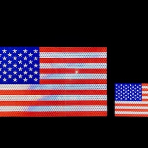 May include: Two American flags, one larger than the other, are displayed against a black background. Both flags are made of reflective material, creating a shimmering effect.