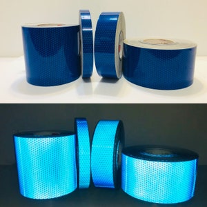 Könnte beinhalten: Zwei Rollen blaues reflektierendes Klebeband und zwei Rollen hellblaues reflektierendes Klebeband. Das Klebeband ist rautenförmig und hat ein Gittermuster.