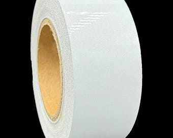May include: A roll of white reflective tape. The tape is on a brown cardboard core.