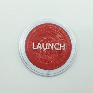 May include: A red button with a white border and the word "LAUNCH" printed in white.