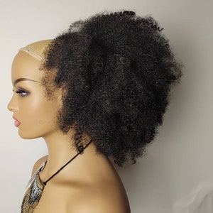 May include: A black afro hairpiece with a brown mesh base. The hairpiece is styled in a high ponytail.