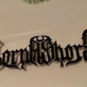 Pode incluir: Design gráfico preto e branco com o texto "Corpse Sword" em uma fonte gótica.