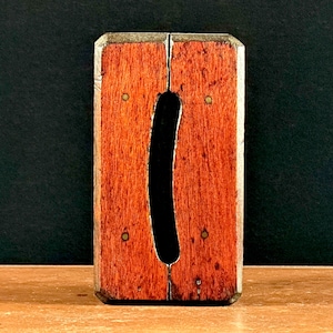 May include: A wooden level with a brass inlay and a cutout in the shape of a letter "I".