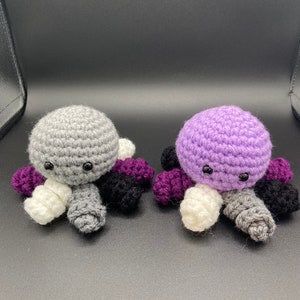 May include: Two crocheted octopus plushies, one gray and one purple, with white, black, and purple tentacles.