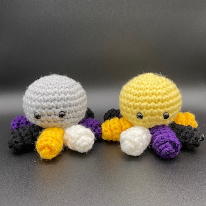 May include: Two crocheted octopus plushies, one gray with black, white, and yellow tentacles, and one yellow with black, white, and purple tentacles.