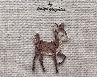 以下が含まれることがあります： 「MON JOURNAL D'ALBUM」と「by design graphics」の文字が黒で刺繍されたベージュの日記帳の表紙。茶色の鹿の刺繍が表紙に施されています。