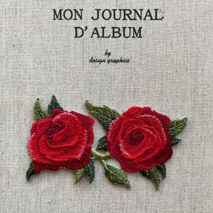 May include: Embroidered journal cover with the text "MON JOURNAL D'ALBUM" and "by design graphics". Two vibrant red roses with green leaves are embroidered on a beige fabric background.