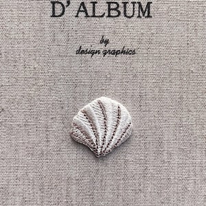 K&ouml;nnte beinhalten: Nahaufnahme eines beigefarbenen Stoffes mit dem Text "MON JOURNAL D'ALBUM" und "by design graphics" in Schwarz. Eine kleine, gestickte Muschel ist unten zentriert. Der Stoff hat ein strukturiertes Aussehen.