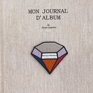 Puede incluir: Parche bordado con forma de diamante con un diseño geométrico en tonos grises, morados, naranjas, rojos y azules. El parche está sobre una tela beige con el texto "MON JOURNAL D'ALBUM" y "by design graphics".