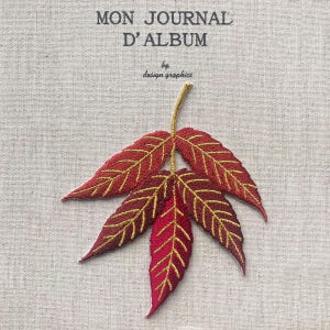 Może przedstawiać: Haftowany wzór czerwonego i złotego liścia na jasnobeżowej tkaninie. Liść ma szczegółowy wzór ze złotymi przeszyciami. Tekst "MON JOURNAL D'ALBUM" znajduje się na górze, a pod nim "by design graphics".