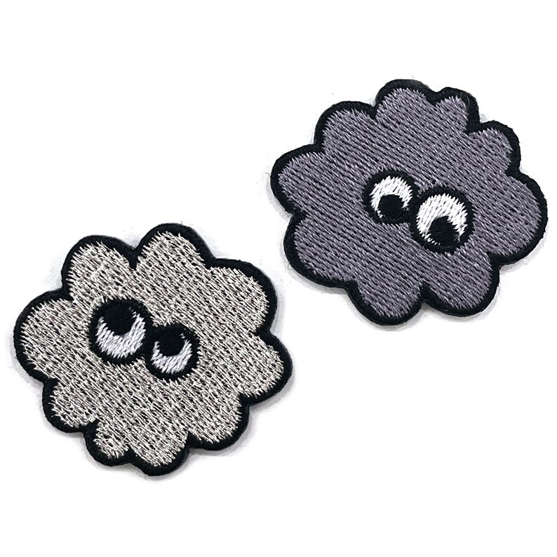 K&ouml;nnte beinhalten: Zwei gestickte Aufn&auml;her in Form von Wolken mit Cartoon-Augen. Einer ist hellgrau, der andere dunkelgrau. Beide haben schwarze Umrisse und wei&szlig;e und schwarze Augen. Diese Aufn&auml;her eignen sich perfekt zum Aufn&auml;hen auf Kleidung oder Accessoires.