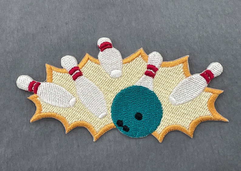 May include: Embroidered patch featuring a bowling scene. The design includes white bowling pins with red stripes, a teal bowling ball, and a yellow burst background. The patch is likely for apparel or accessories.