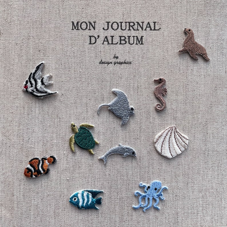 K&ouml;nnte beinhalten: Gestickte Meeresbewohner und eine Muschel auf beigem Stoff. Die Sammlung umfasst Fische, einen Stechrochen, ein Seepferdchen, eine Schildkr&ouml;te, einen Delfin und einen Oktopus. Der Text "MON JOURNAL D'ALBUM" ist oben zu sehen.