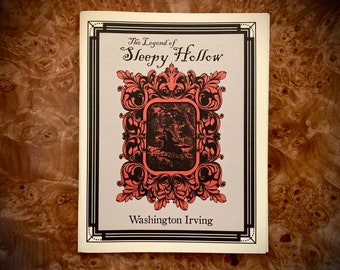 May include: A book cover for "The Legend of Sleepy Hollow" by Washington Irving. The cover features a decorative frame with a central image and text. The frame is coral-colored with black accents, and the background is light gray.