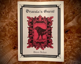 Könnte beinhalten: Ein Buchcover mit einer Schwarzweißillustration eines Wolfes in einem roten Rahmen mit verzierten schwarzen Details. Der Titel lautet "Dracula's Guest" und der Autor ist "Bram Stoker".