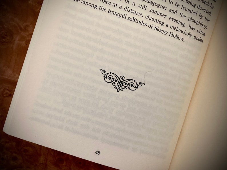 K&ouml;nnte beinhalten: Offene Buchseite mit gedrucktem Text und einer dekorativen schwarzen Verzierung. Die Seitenzahl 48 ist unten sichtbar. Der Text ist in schwarzer Schrift auf einer wei&szlig;en Seite.