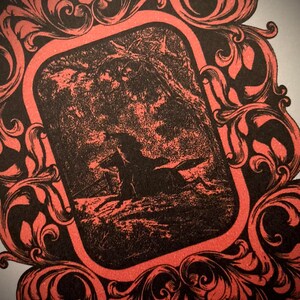 K&ouml;nnte beinhalten: Gerahmte Illustration in Schwarz und Rot. Das zentrale Bild zeigt eine Silhouette einer Person auf einem Pferd in einer Waldlandschaft. Der Rahmen hat aufwendige, wirbelnde Blumenmuster, die ein Vintage-Feeling erzeugen. Das Design ist dekorativ.