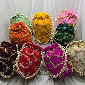 Op de afbeelding: Een verzameling kleurrijke zakjes met trekkoord. Elk zakje heeft een andere kleur, waaronder oranje, geel, roze, groen, rood, paars en crème. Ze zijn versierd met gouden borduursels en een parelrand.