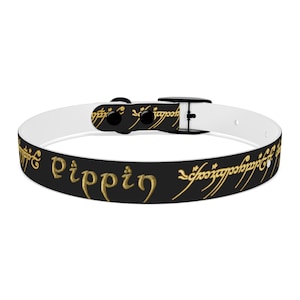 Puede incluir: Collar de perro blanco y negro con una inscripción dorada que dice "Pippin" y un patrón repetido de la inscripción en un círculo.