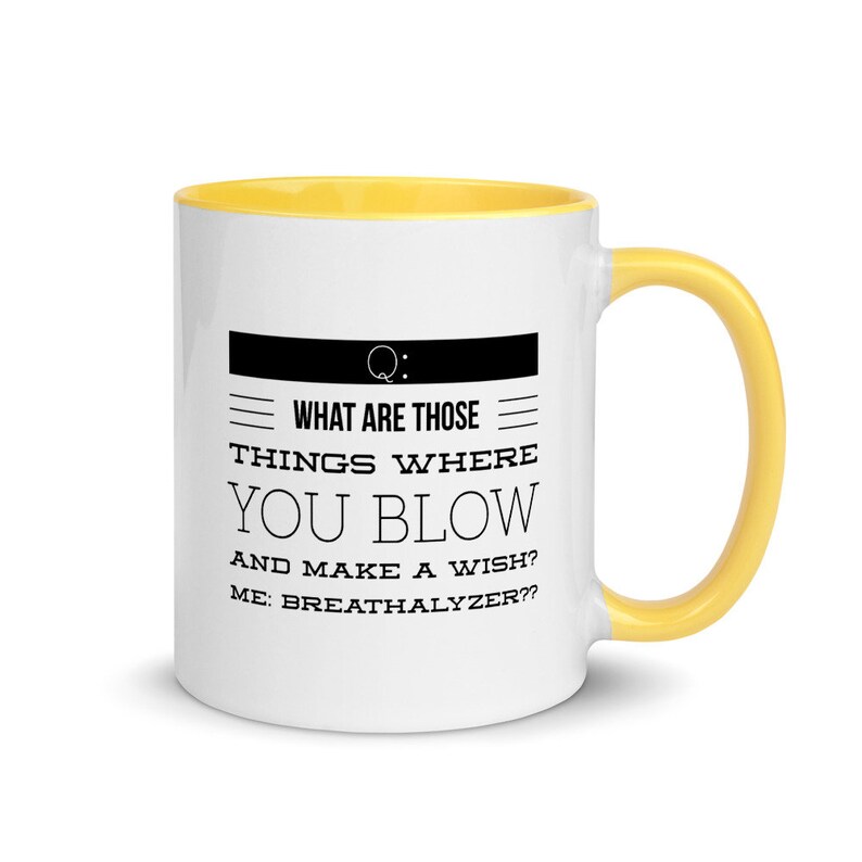 May include: White ceramic mug with a yellow interior and handle. The mug features black text that reads "WHAT ARE THOSE THINGS WHERE YOU BLOW AND MAKE A WISH? ME: BREATHALYZER??" A humorous gift idea.