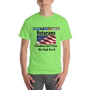 May include: A neon green t-shirt with the word "Veterans" above a waving American flag. The shirt also features the text "Freedom Isn't Free We Paid For It" and the names of the military branches.