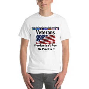 May include: White t-shirt featuring the text "Veterans" above an American flag graphic. The shirt also displays the text "Freedom Isn't Free We Paid For It" and the names of the military branches.