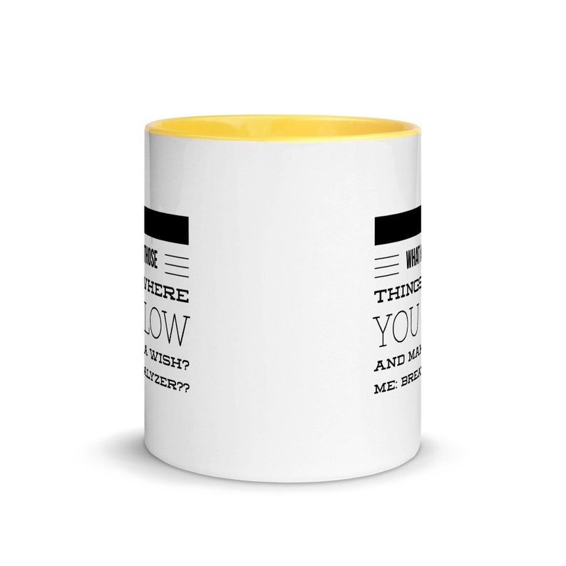 May include: White ceramic coffee mug with a yellow interior. The mug features black text that reads "Where do wishes flow?" and "What things make you..." on opposite sides. A simple, everyday item.