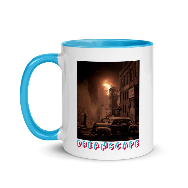 May include: White ceramic mug with a blue interior and handle. The mug features a vintage cityscape illustration with a classic car and the word "DREAMSCAPE" in red and blue text.