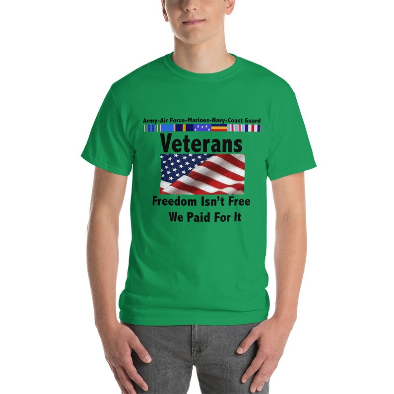 May include: A green t-shirt with the word "Veterans" above a waving American flag. The shirt also features the text "Freedom Isn't Free We Paid For It" and ribbons representing the Army, Air Force, Marines, Navy, and Coast Guard.