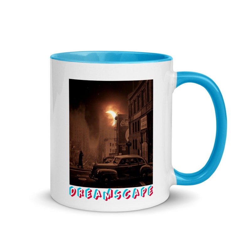 May include: White ceramic mug with a blue interior and handle. The mug features a vintage-style illustration of a city scene with a classic car and the word "DREAMSCAPE" in colorful text.