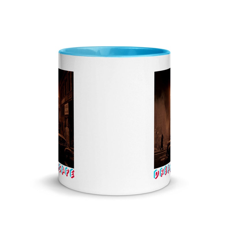 May include: White ceramic mug with a light blue interior. The mug features a dark, detailed illustration of a city scene with cars and buildings. The word "DREAMSCAPE" is printed in red and blue on the mug.