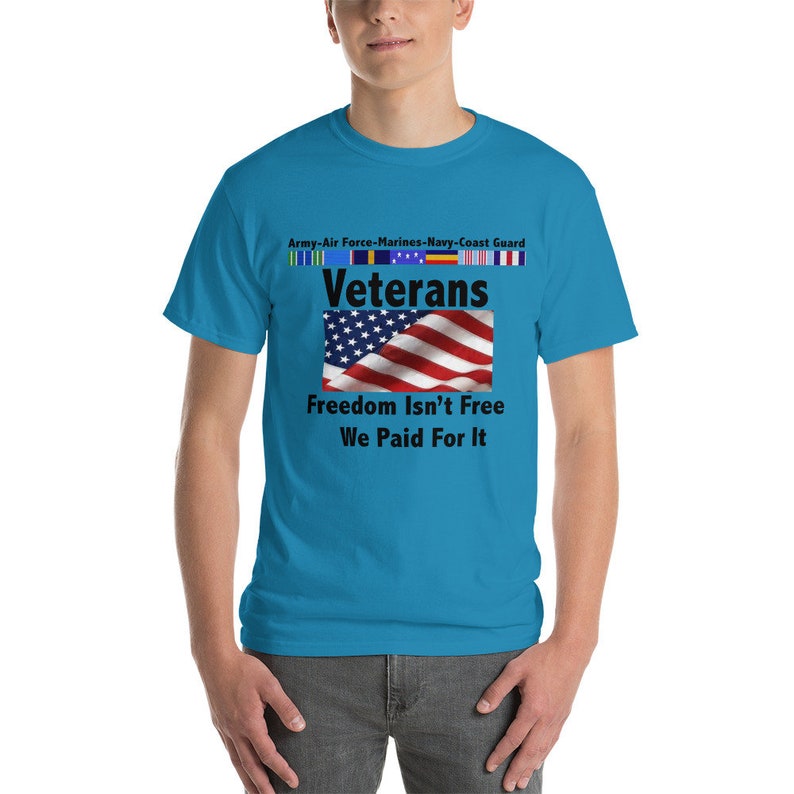 May include: A turquoise t-shirt featuring the text "Veterans" above an American flag graphic. Below the flag, the shirt reads "Freedom Isn't Free, We Paid For It." Above the word "Veterans" are the words "Army-Air Force-Marines-Navy-Coast Guard."