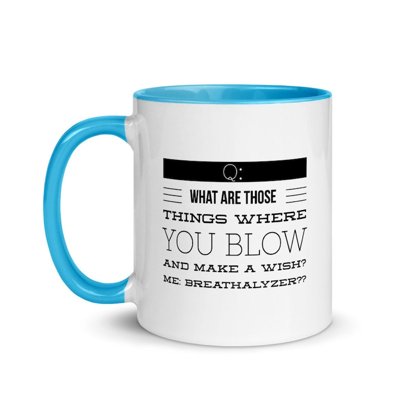 May include: White ceramic mug with a blue handle and interior. The mug features the text "WHAT ARE THOSE THINGS WHERE YOU BLOW AND MAKE A WISH? ME: BREATHALYZER??" in a black, bold font. The mug is designed for beverages.