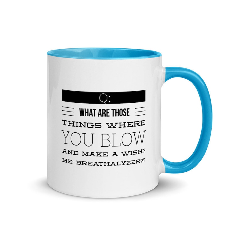 May include: White ceramic mug with a blue interior and handle. The mug features the text "WHAT ARE THOSE THINGS WHERE YOU BLOW AND MAKE A WISH? ME: BREATHALYZER??" in black font, with a black rectangle above the text.