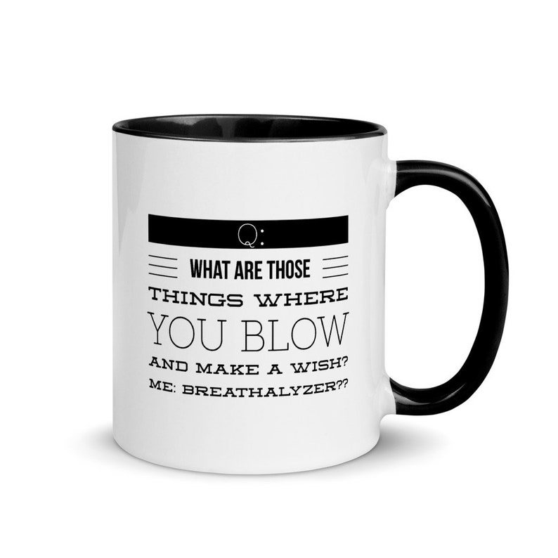 May include: White ceramic mug with a black interior and handle. The mug features the text "WHAT ARE THOSE THINGS WHERE YOU BLOW AND MAKE A WISH? ME: BREATHALYZER??" in black, with a black rectangular design at the top.