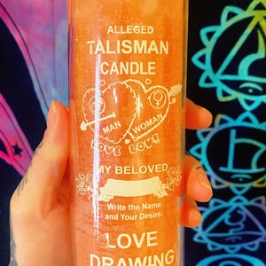 May include: Orange Alleged Talisman Candle in a clear glass jar. The candle has white text that reads "Man Love Woman Love My Beloved" and "Love Drawing". The label also says "Write the Name and Your Desire."